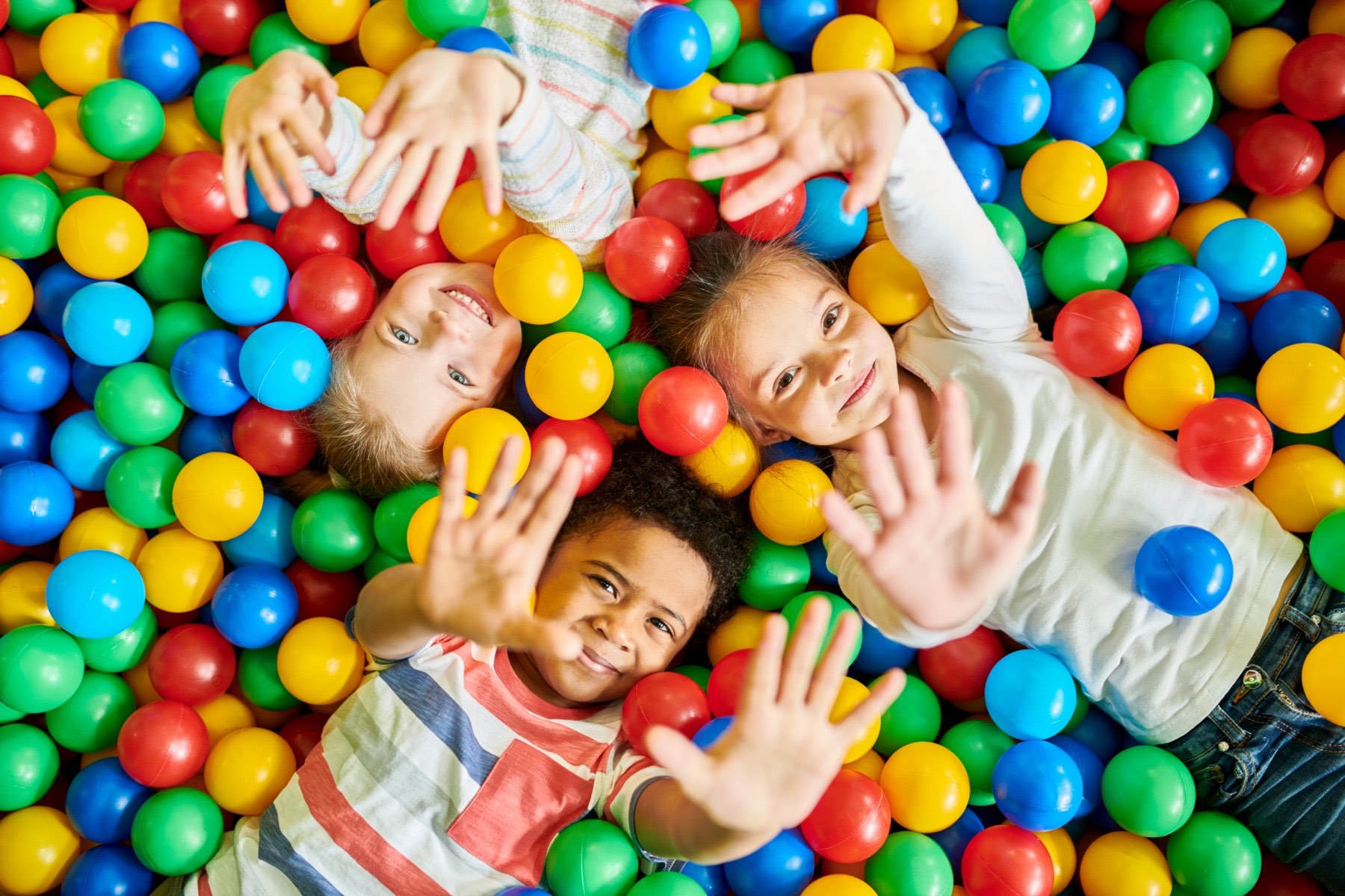 Three children lying in a ball pit