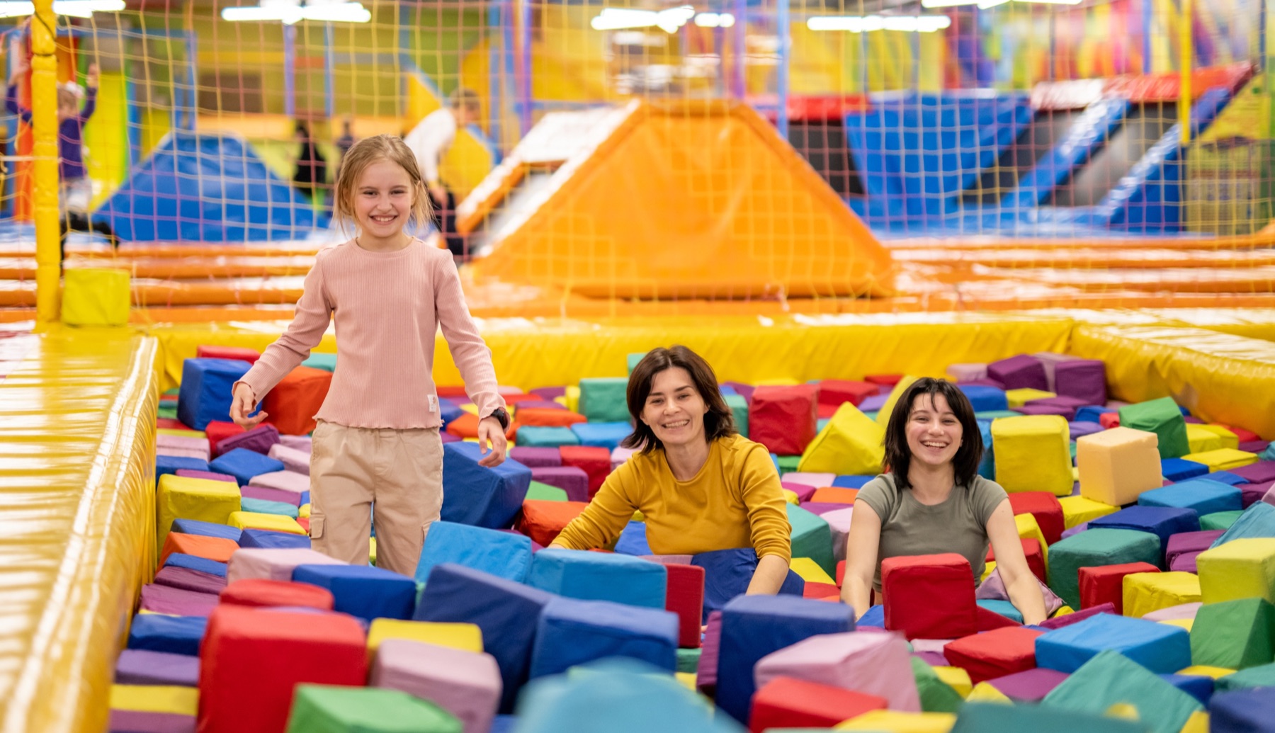 A girl and two adults in a pit of foam blocks
