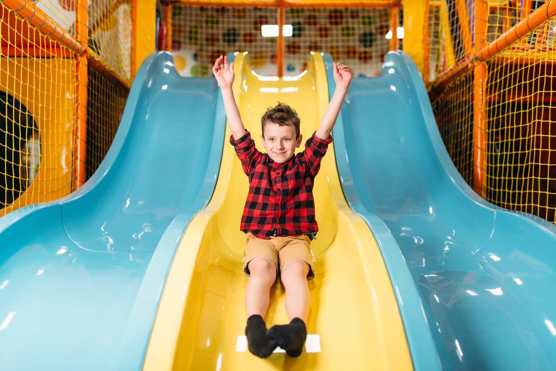 A boy coming down a slide with his arms up