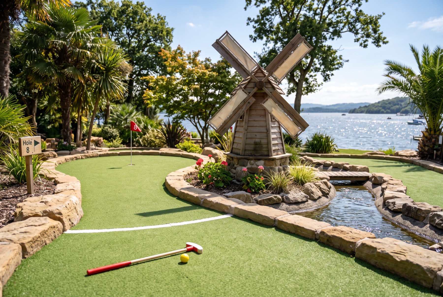 A themed hole with a windmill and a water channel on a lakeside course