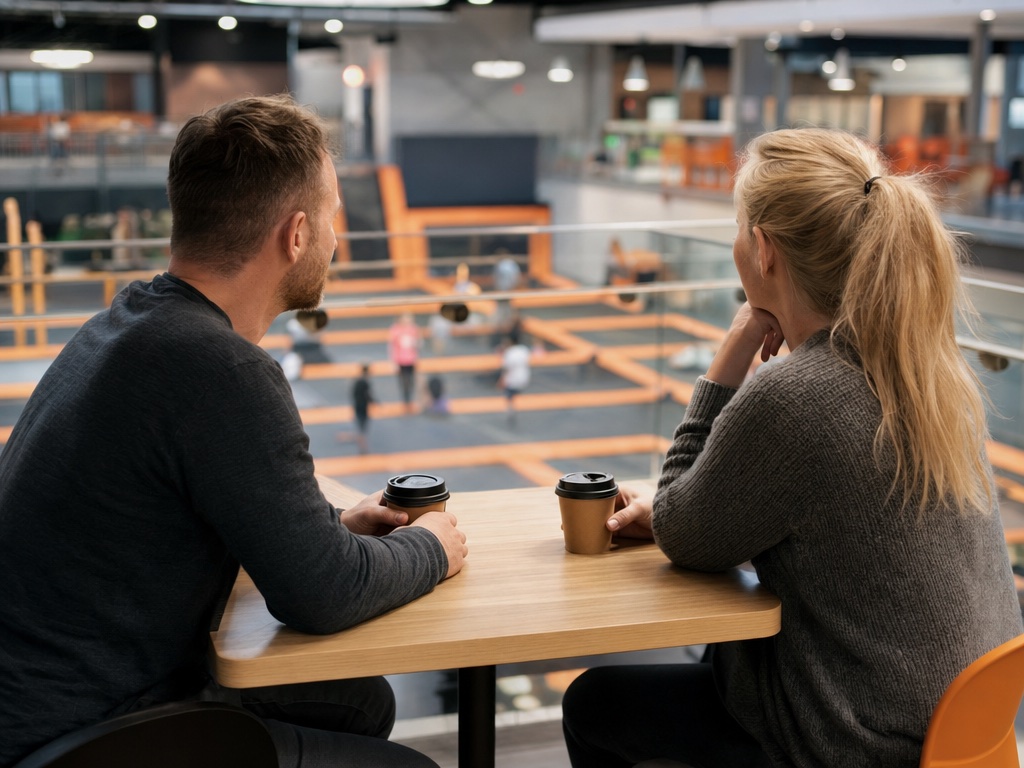 Two adults with coffee at a cafe table above the courts