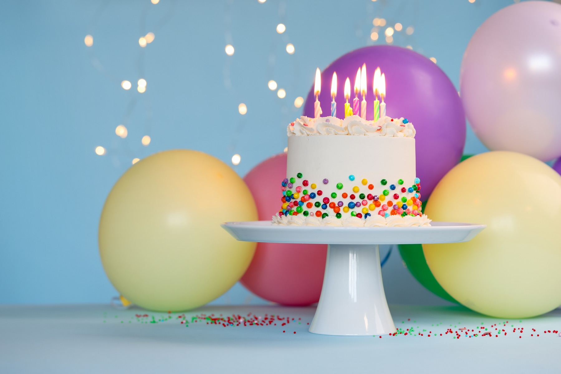 A birthday cake with candles among balloons